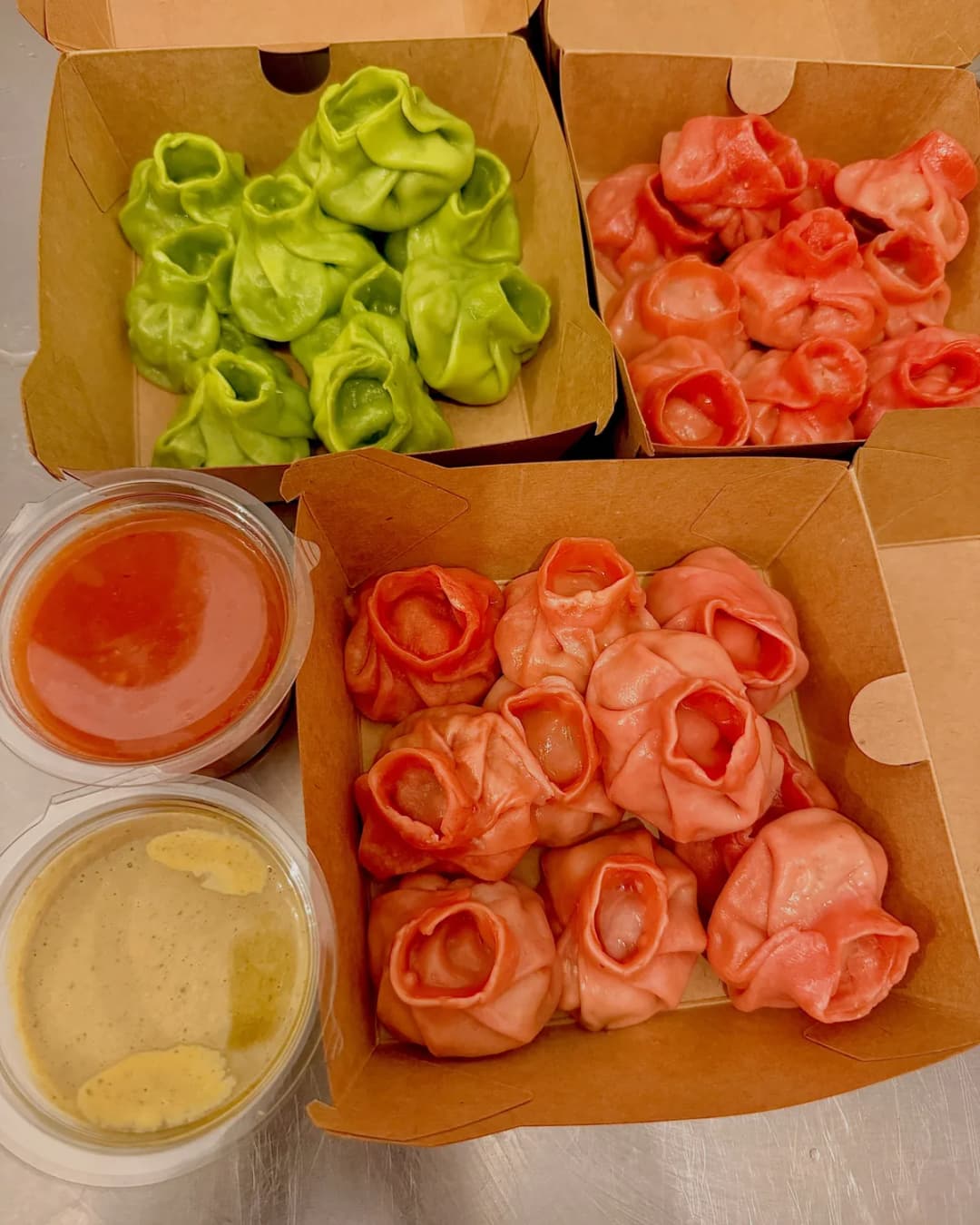 Momo verdi e rosa nelle loro scatole, con entrambe le salse della casa